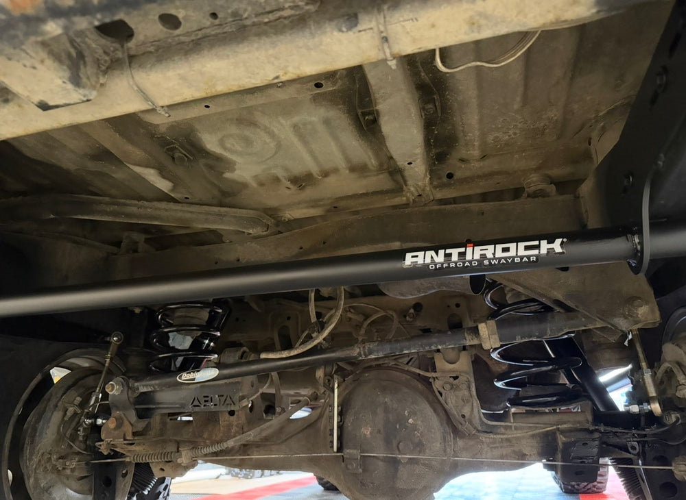 BPF 80 Series Land Cruiser RockJock AntiRock Frame Mounting Plates installed beneath a Toyota Land Cruiser with visible sway bar suspension and axle