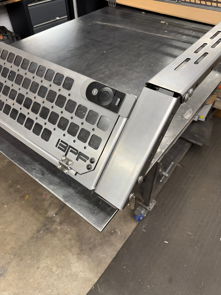 Close-up view of a metallic bed rack corner with perforated grill mesh and lock mechanism, part of the 05-26 Tacoma Bed Rack fits 2nd,3rd and 4th gen Tacomas, designed for secure cargo storage and durability.