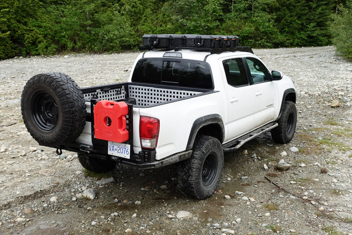 White off-road truck equipped with BPF Universal Pelican Vault V700 Case Mounting brackets holding gear on the roof rack and rear bed, parked on rocky terrain.