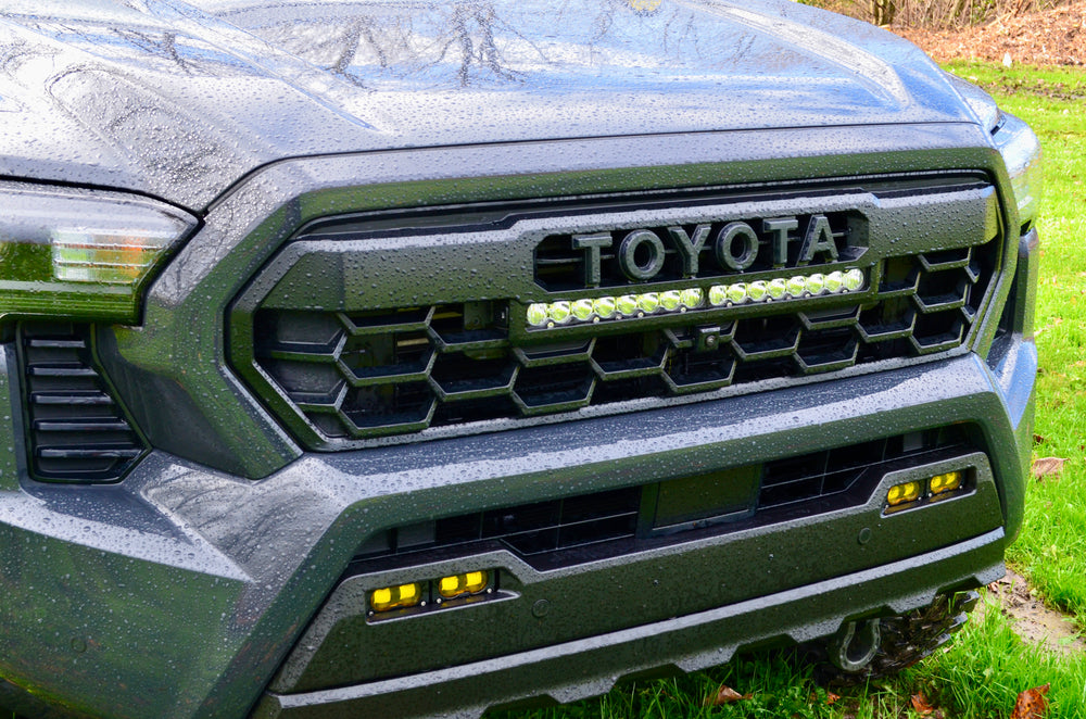 Close-up of a wet black truck front featuring the 2024 Trailhunter Grille with BPF letters installed, showcasing a rugged hexagonal grill mesh and integrated LED light bar.