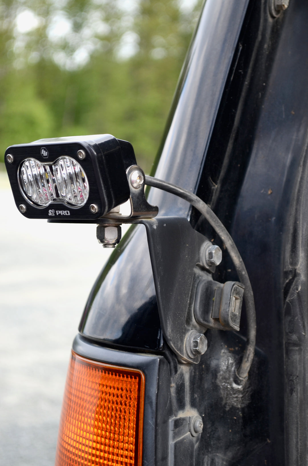BPF 80 series Land Cruiser rear light brackets 92-97 installed on a black vehicle with a mounted LED off-road light, showcasing sturdy metal construction and secure bolt-on fitment.