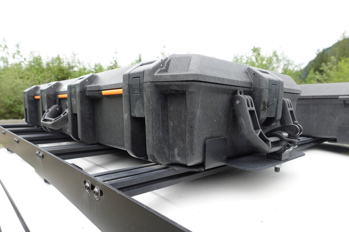 BPF Universal Pelican Vault V700 Case Mounting brackets securing multiple Pelican Vault cases on a black roof rack, designed for heavy-duty overlanding storage and secure transport.