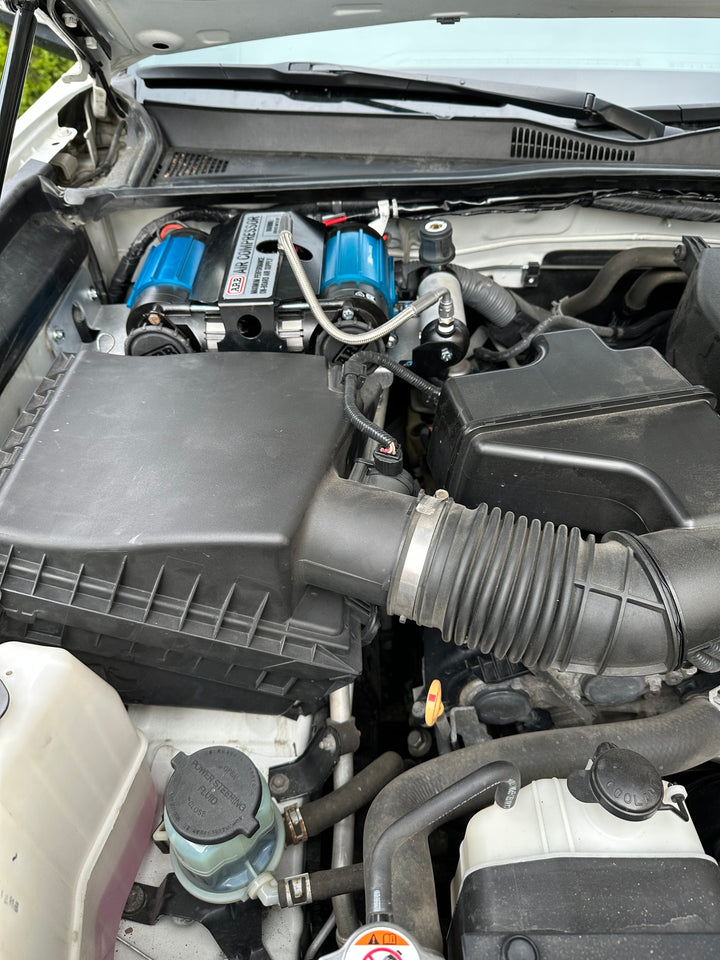 Engine bay featuring the BPF 2016-2023 3rd Gen Tacoma Compressor mount with blue compressors installed, showing a clean and organized setup with hoses and wiring in place.