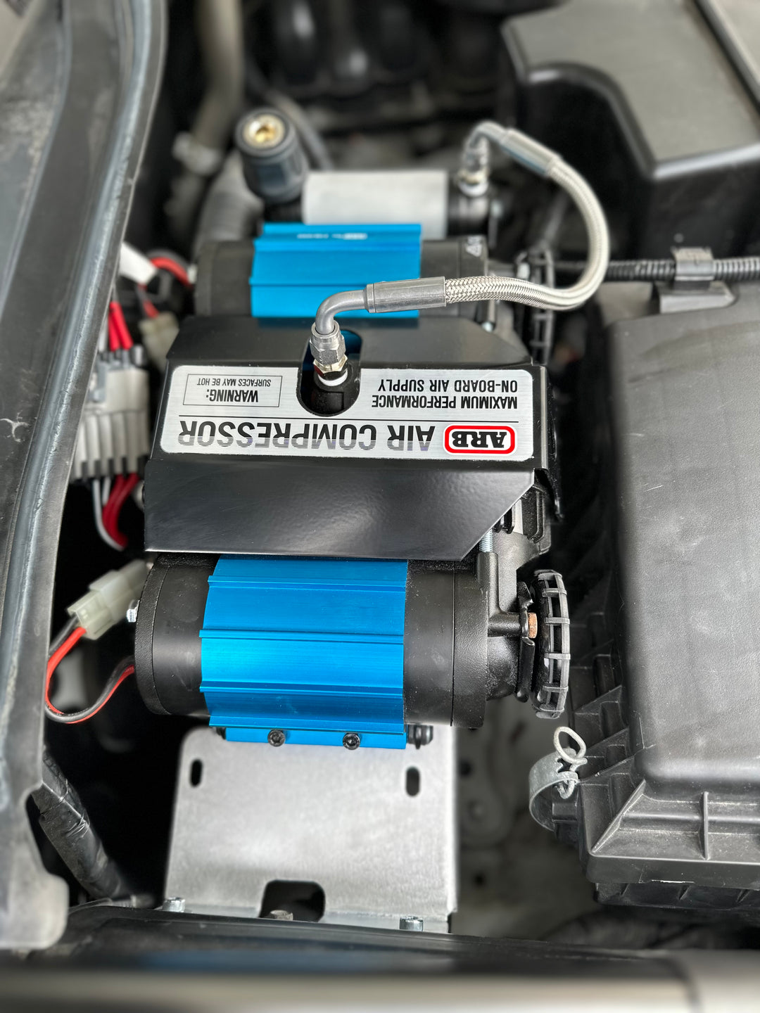 Close-up of an ARB air compressor mounted securely with the BPF 2016-2023 3rd Gen Tacoma Compressor mount inside a vehicle engine bay, showing detailed installation and components.