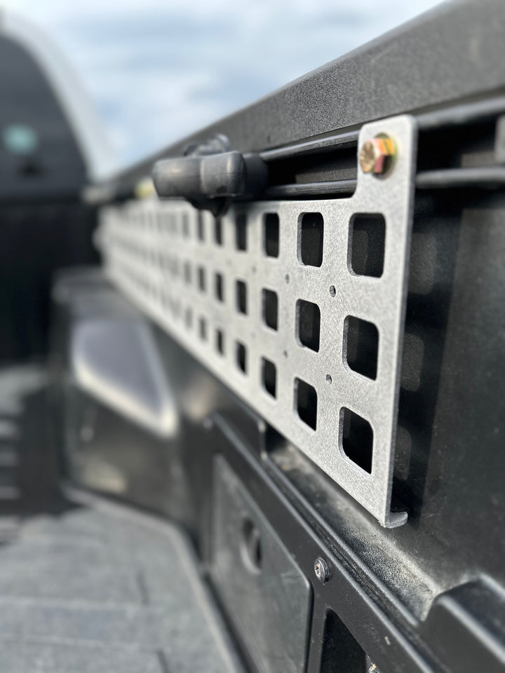 Close-up view of a powder-coated metal MOLLE panel securely mounted on a truck bed rail, showcasing the high-quality BPF 05-23 Tacoma bed Molle panels designed for durable and organized gear storage.