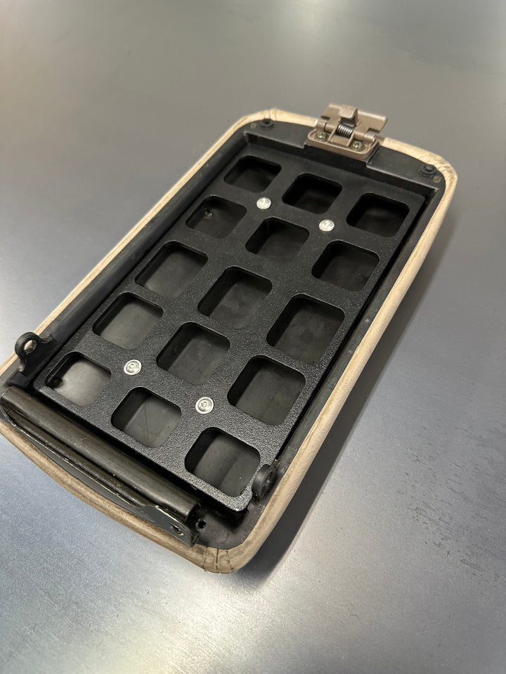 BPF 80 Series Land Cruiser/LX450 Center Console Molle Panel featuring a black powder coated molle mounting grid inside a beige center console lid on a gray surface.