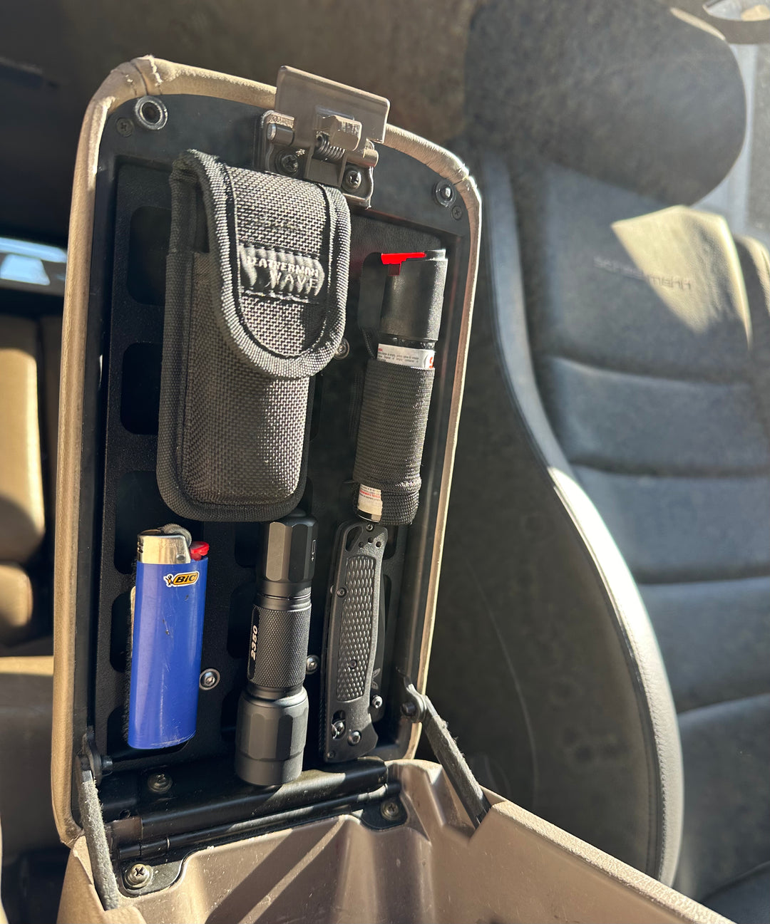 BPF 80 Series Land Cruiser/LX450 Center Console Molle Panel mounted inside a vehicle with organized storage for lighter, flashlight, knife, and pepper spray, showcasing a durable and practical setup.