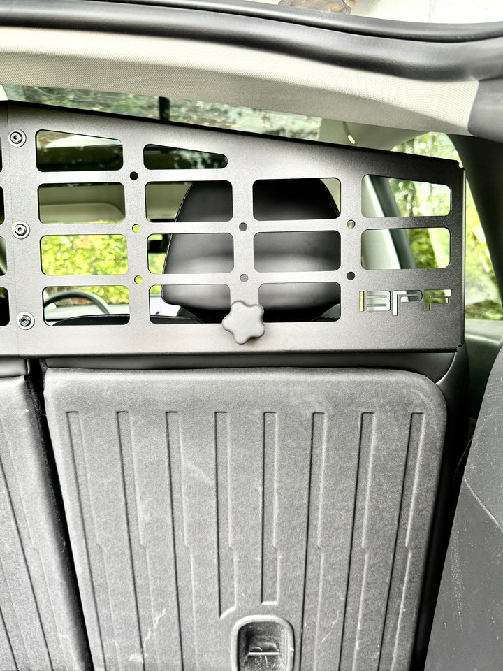 Interior view of a BPF Molle Style Pet Barrier Tesla Model Y 2020-CURRENT installed behind the rear seats, featuring a black metal grid design with ventilation openings and the BPF logo.