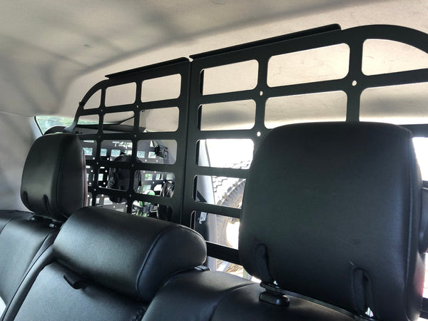 Interior view of a vehicle showing a black metal pet barrier installed behind the front seats, designed to keep pets safely separated from the passenger area.