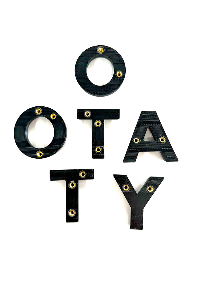 BPF 2024+ TRD PRO &amp; Trailhunter Grille Letters spelling "OTATY" in black with brass-colored rivets, designed for CNC fabrication and heavy-duty overlanding gear customization.