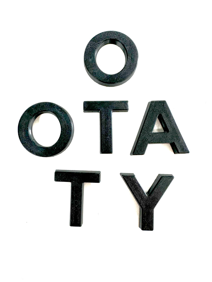 Black textured grille letters spelling "OTATY" arranged on a white background, part of the BPF 2024+ TRD PRO &amp; Trailhunter Grille Letters set designed for truck customization.