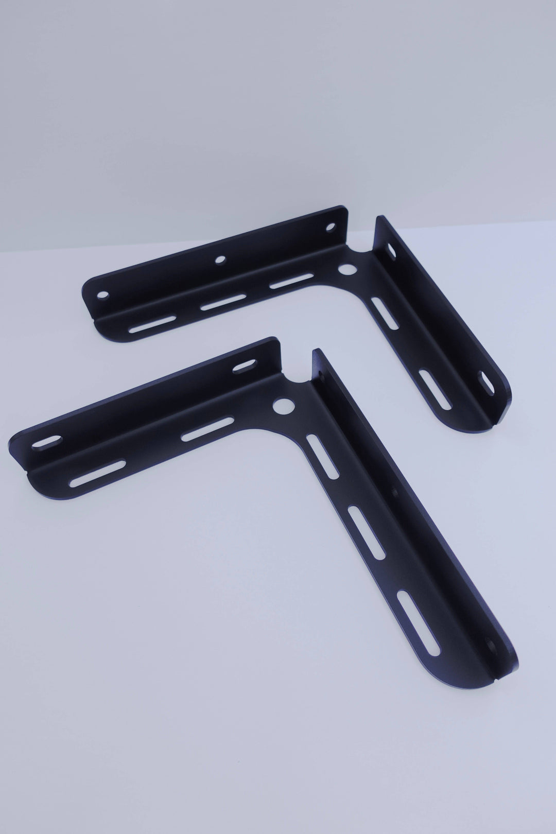 Two black powder-coated metal brackets with multiple elongated holes designed for mounting, identified as BPF 2005-2023 Toyota Tacoma Bed Stiffeners.