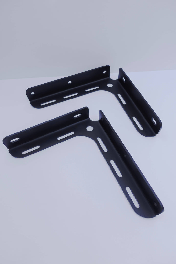 Two black powder-coated metal brackets with multiple elongated holes designed for mounting, identified as BPF 2005-2023 Toyota Tacoma Bed Stiffeners.