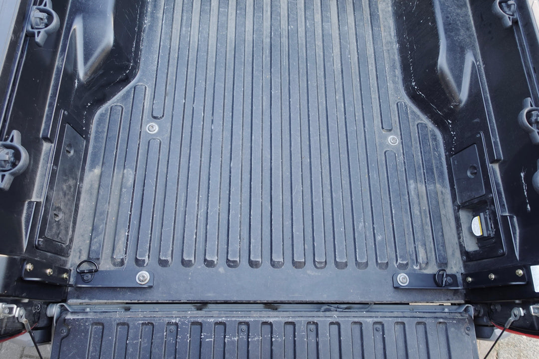Close-up view of a black truck bed featuring installed BPF 2005-2023 Toyota Tacoma Bed Stiffeners with a textured surface and durable construction for enhanced bed strength and support.