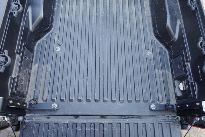 Close-up view of a black truck bed featuring installed BPF 2005-2023 Toyota Tacoma Bed Stiffeners with a textured surface and durable construction for enhanced bed strength and support.
