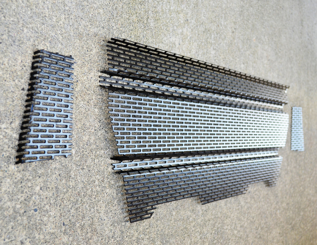 BPF 2005-2011 Toyota Tacoma Raptor Style Mesh and Lettering laid out on a concrete surface showing the powder-coated grill mesh pieces with a black finish and silver lettering detail.