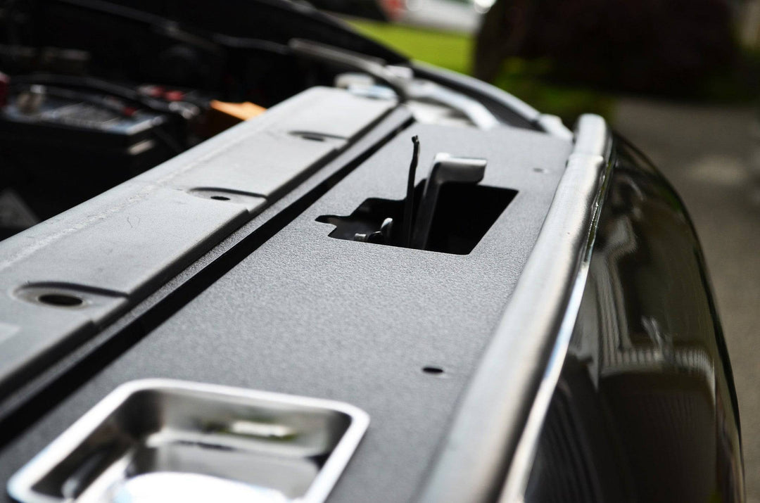 Close-up view of a black BPF 05-11 Toyota Tacoma Radiator Cover installed on a truck, showcasing its textured, durable surface with an OEM fitment design.