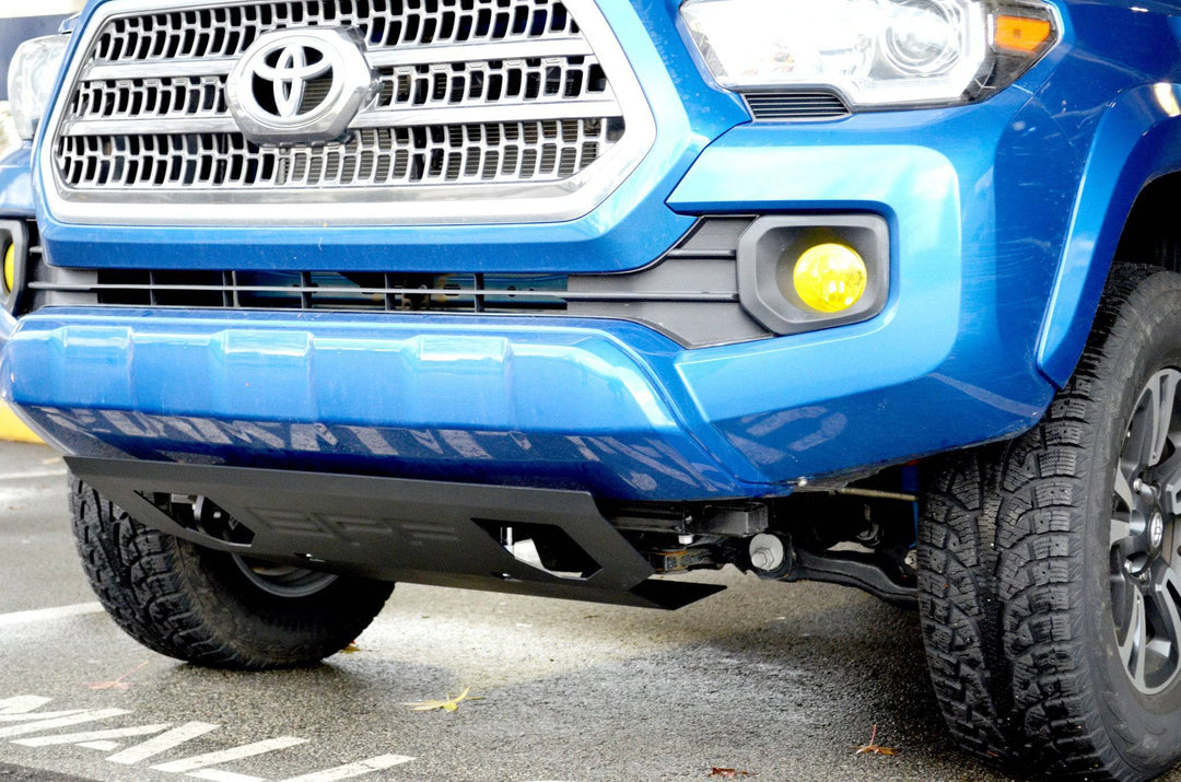 Close-up of a blue Toyota Tacoma featuring the installed BPF 2016-2023 Tacoma Skid Plate with powder-coated finish and CNC fabricated design for added front-end protection.