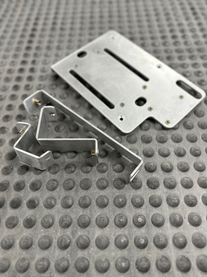 BPF 80 series Land cruiser Fuse block mount showing CNC fabricated metal mounting brackets and base plate resting on textured rubber mat background.
