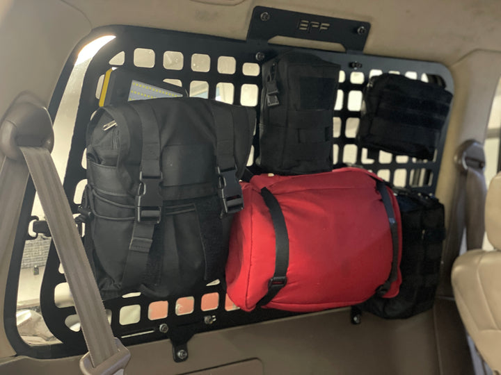 BPF 1990-1997 Toyota Land Cruiser Storage Panels installed inside vehicle, featuring black grid panel with mounted black and red storage bags for organized overlanding gear.