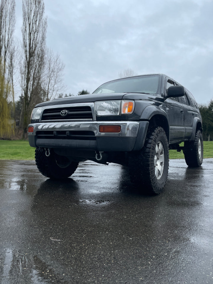 Toyota 3rd generation 4Runner parked on wet pavement with heavy-duty BPF 3rd gen 4Runner Tow Hook Set 1996-2002 installed, featuring durable steel tow hooks and rugged off-road tires.