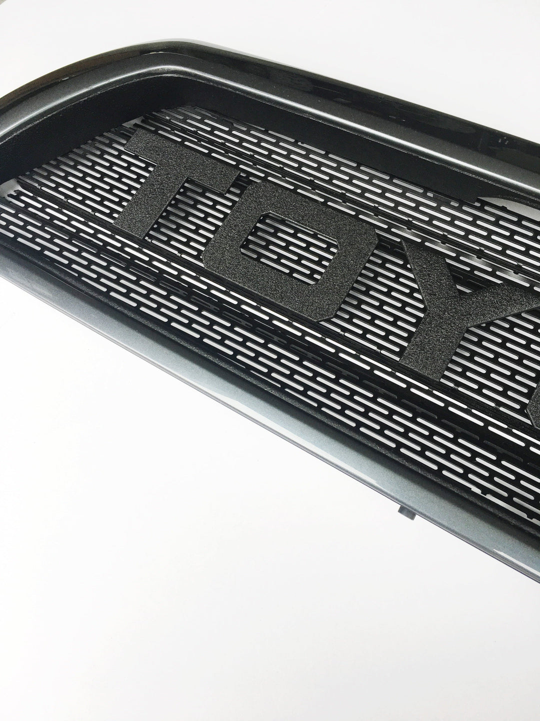Close-up view of a black textured BPF 03-09 Toyota 4runner Grill with bold raised letters and a precision-cut grill mesh design.