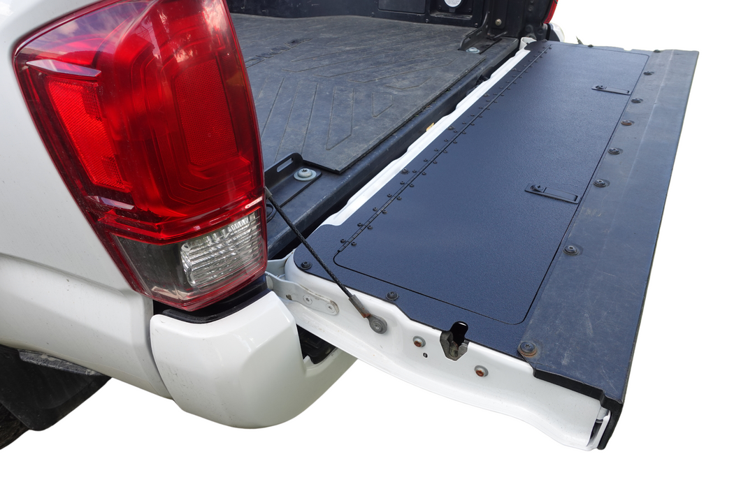 BPF 2016-2023 Toyota Tacoma Tailgate Panel installed on an open white pickup truck tailgate, featuring a durable textured black surface designed for OEM fitment and heavy-duty use.